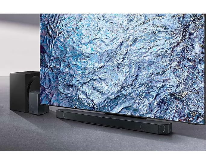 Samsung HW-Q990C sous une télévision avec son caisson et une enceinte sans fil